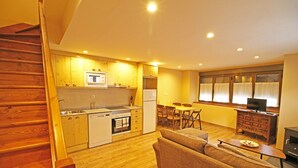 A compact living space with a kitchen, dining area, and a sofa. - Apartamentos Mont Romies Plaza (Naut Aran)