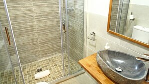 A bathroom with a glass-enclosed shower, a wooden vanity with a stone sink, and a white toilet. - Apartamentos Mont Romies Plaza (Naut Aran)