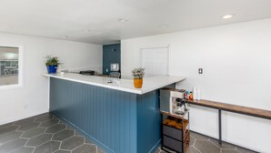 A modern kitchen with a blue island, white walls, and a tiled floor. - Minecart Motor Lodge (Montrose)