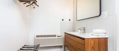 A modern bathroom with a wooden vanity, a mirror, a towel rack, and a radiator.