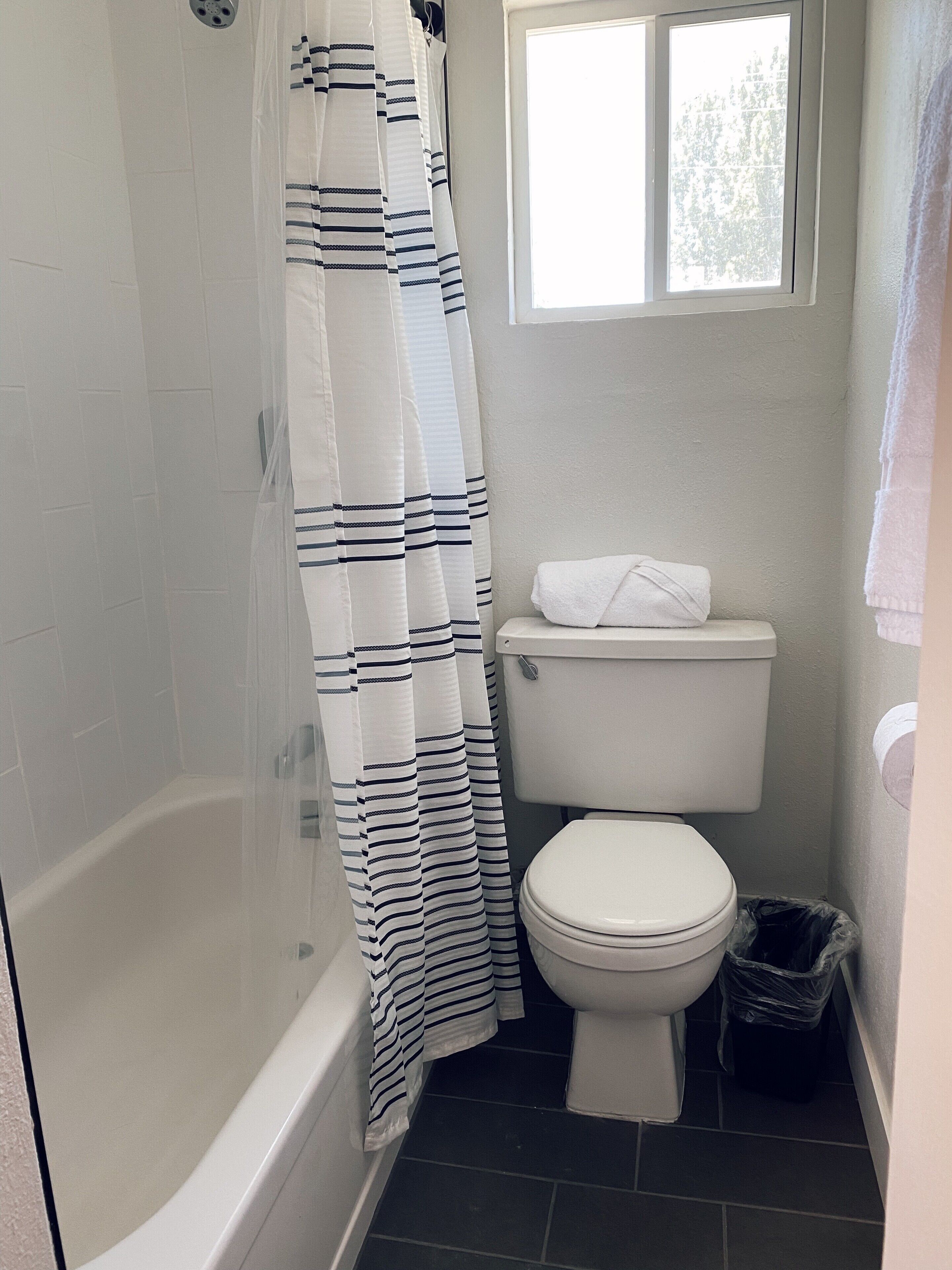 A bathroom with a bathtub, toilet, and a window.