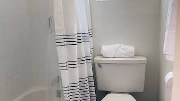 Un baño con bañera, inodoro y ventana.