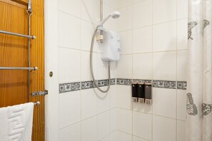 A bathroom with a shower, a towel rack, and a toilet paper holder. - Novelty Suites - Roslin Street (Aberdeen)