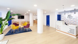 A modern reception area with a blue door, a white reception desk, and colorful chairs. - My City Hotel (Puerto de la Cruz)