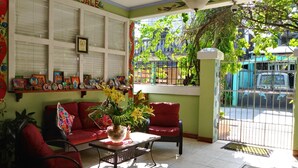 A room with a red sofa, a coffee table with a vase of flowers, and a wall with a 'SALE' sign.