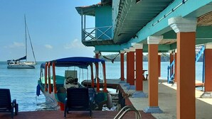 A covered boat dock with a view of the sea and a sailboat in the distance.