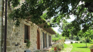 Un bâtiment en pierre doté d’un patio couvert, d’un espace extérieur aménagé pour s’asseoir et d’un jardin.