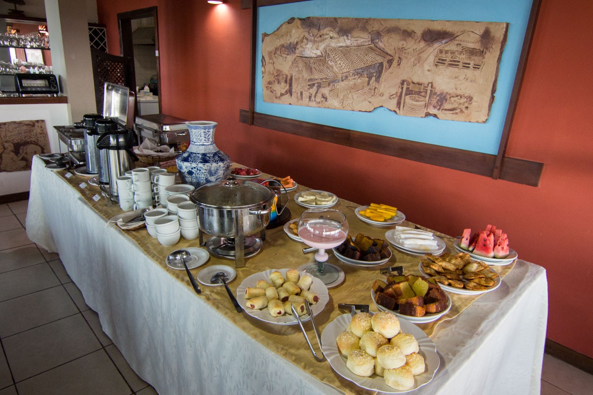 Una mesa de buffet con diversos alimentos y un jarrón azul y blanco grande.