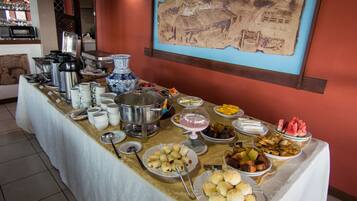 Una mesa de buffet con diversos alimentos y un jarrón azul y blanco grande.