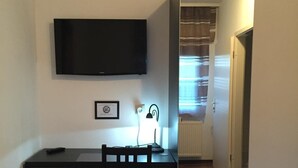 Una habitación pequeña y moderna con escritorio, silla y televisor de pantalla plana en la pared.