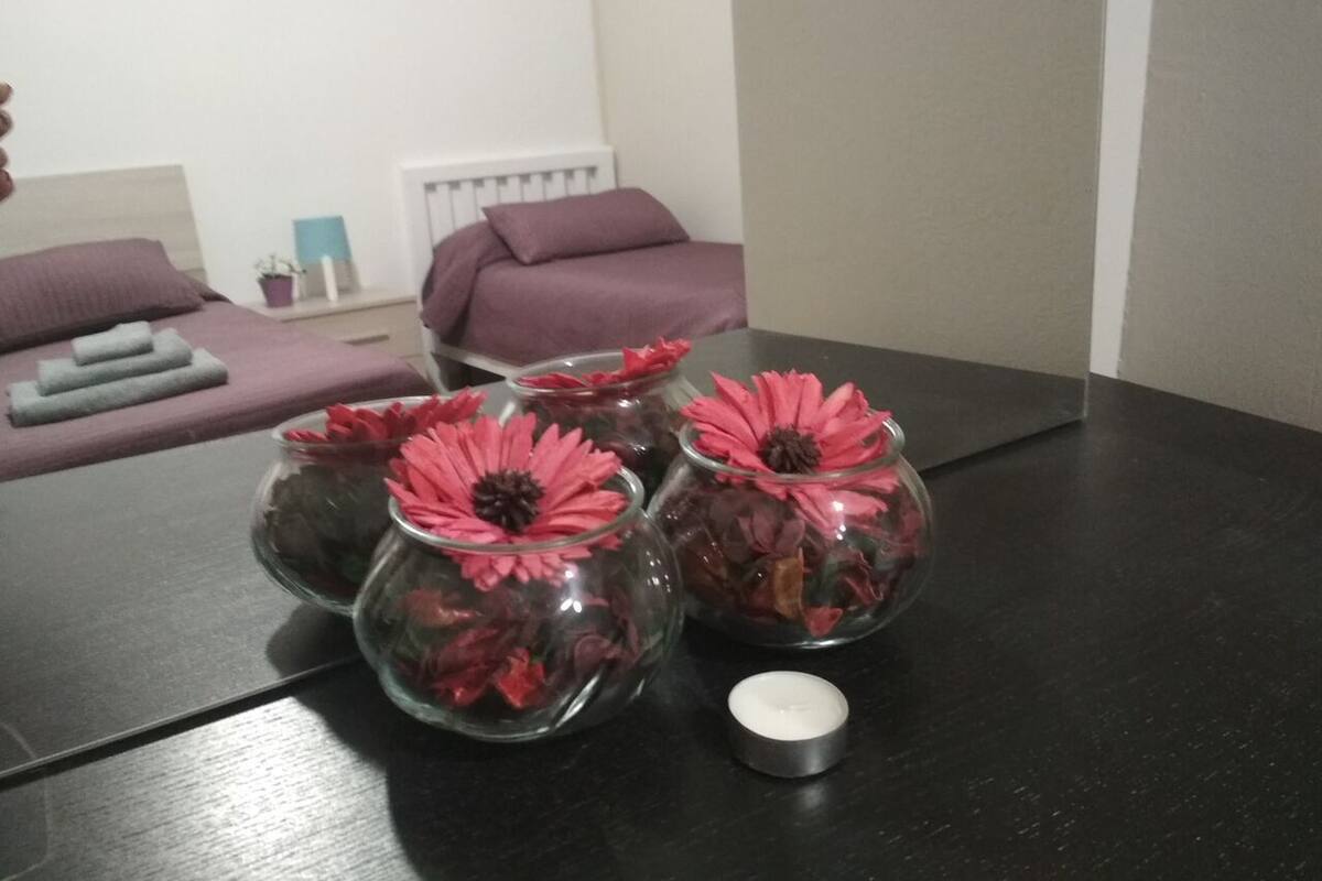 A table with glass vases containing red flowers and a candle.