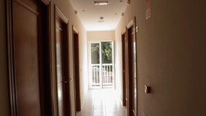 A hallway with wooden doors, a tiled floor, and a glass door leading outside. - Hotel Tamasite (Puerto del Rosario)