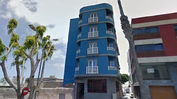A multi-story building with balconies, a red and blue facade, and a visible door.