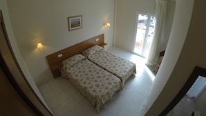 A room with two beds, a ceiling light, a wall-mounted picture, and a window with curtains. - Hotel Tamasite (Puerto del Rosario)