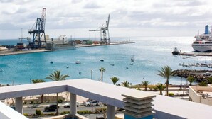 Un port de plaisance situé sur la côte, avec des bateaux, des grues et un grand navire de croisière amarré.