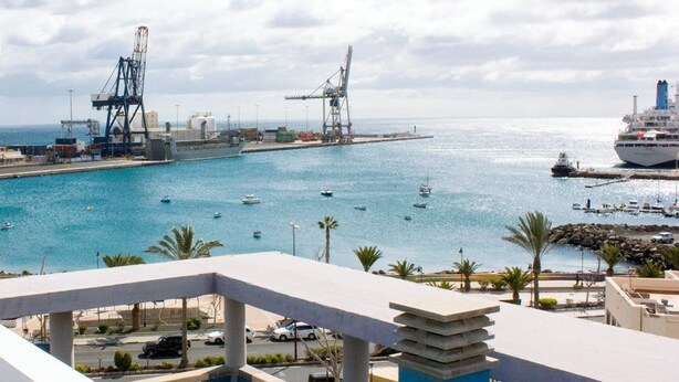 A coastal marina with boats, cranes, and a large cruise ship docked. - Hotel Tamasite (Puerto del Rosario)