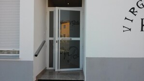 A door with a glass panel and a handle, a metal handrail, and a wall with the text "VIRGIN HILTON". - Hostal Virgen del Pilar (Baza)