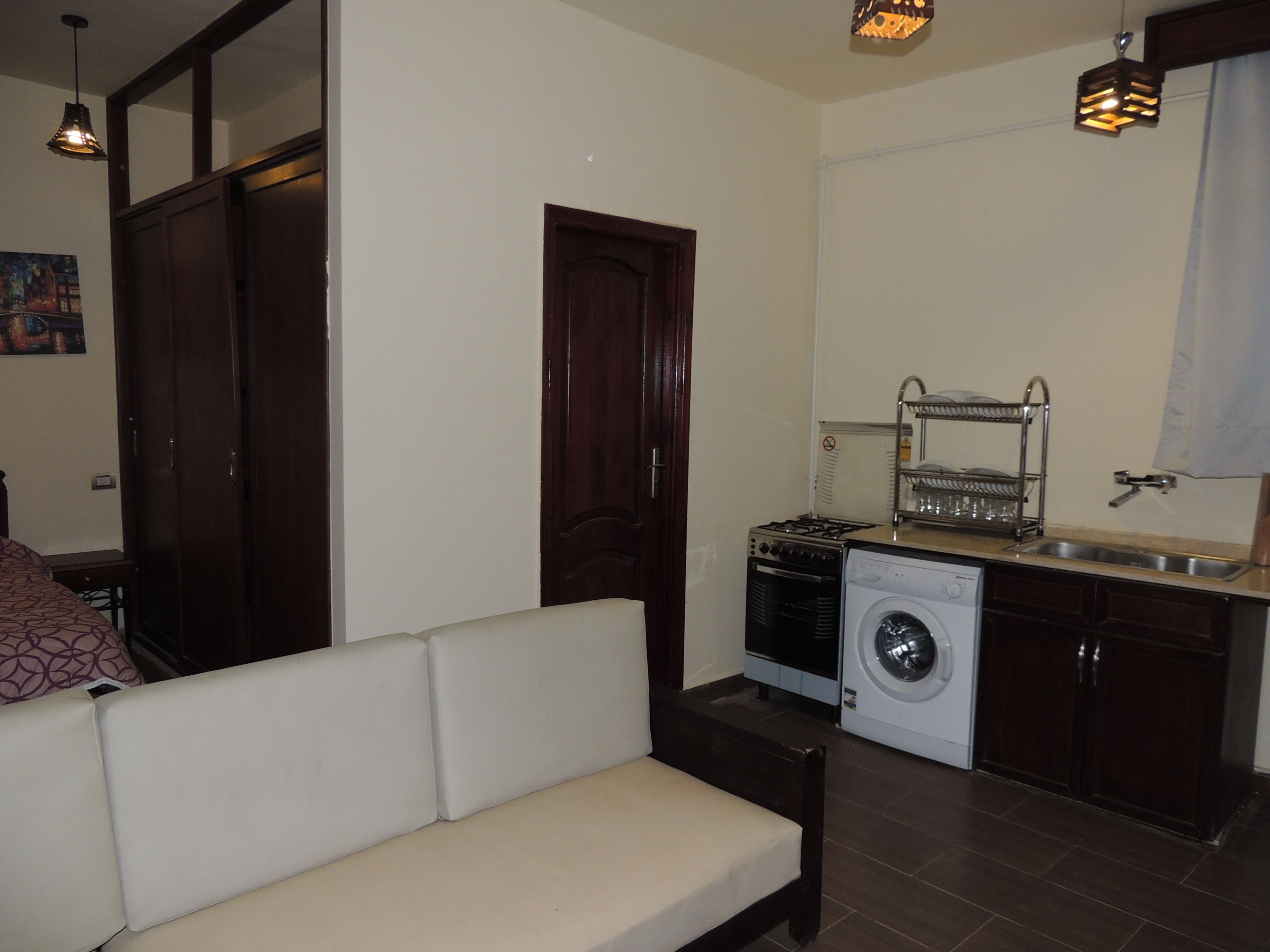 A compact living space with a sofa, a washing machine, a stove, and a sink.