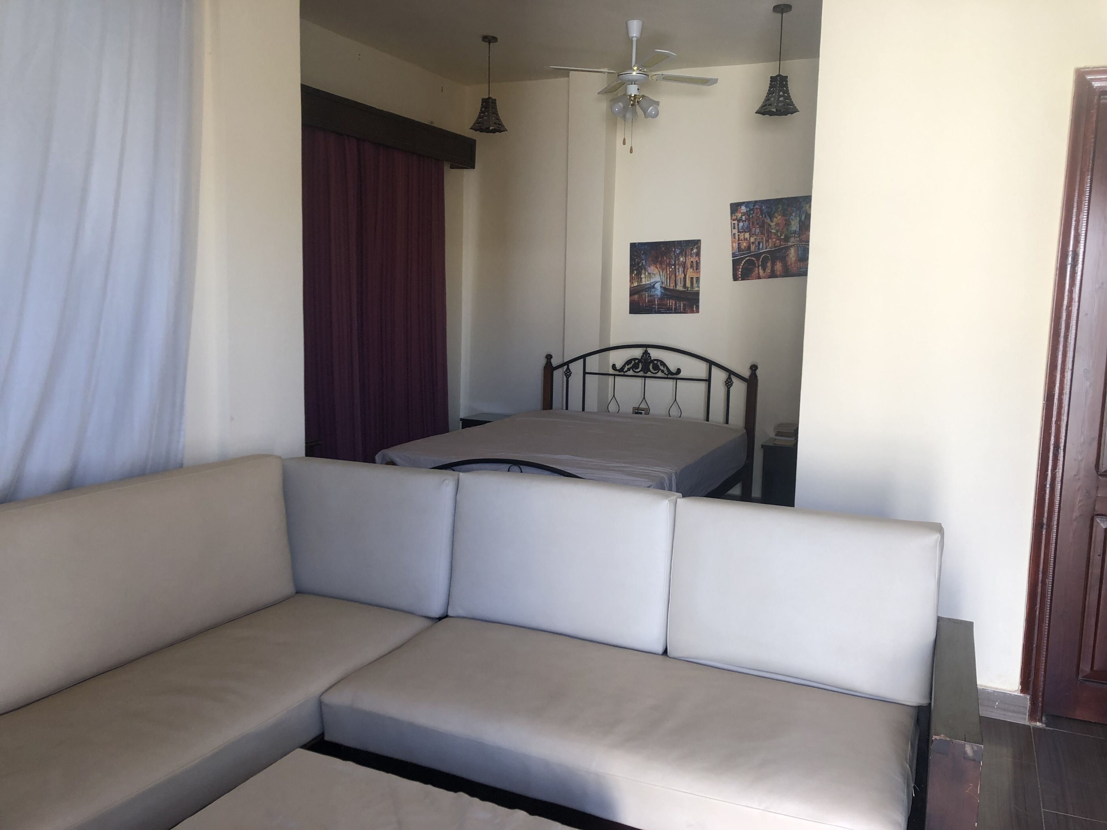 Un dormitorio con cama, sofá, ventilador de techo y una puerta.
