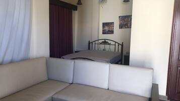 Un dormitorio con cama, sofá, ventilador de techo y una puerta.