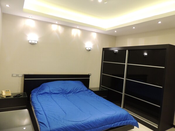 A modern bedroom with a bed, bedside table, and a wardrobe. - Sultan Dusit Villa New Cairo (New Cairo)