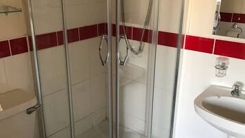 A bathroom with a glass-enclosed shower, a toilet, and a sink.
