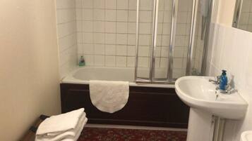 Une salle de bain avec une baignoire, une douche et un lavabo.