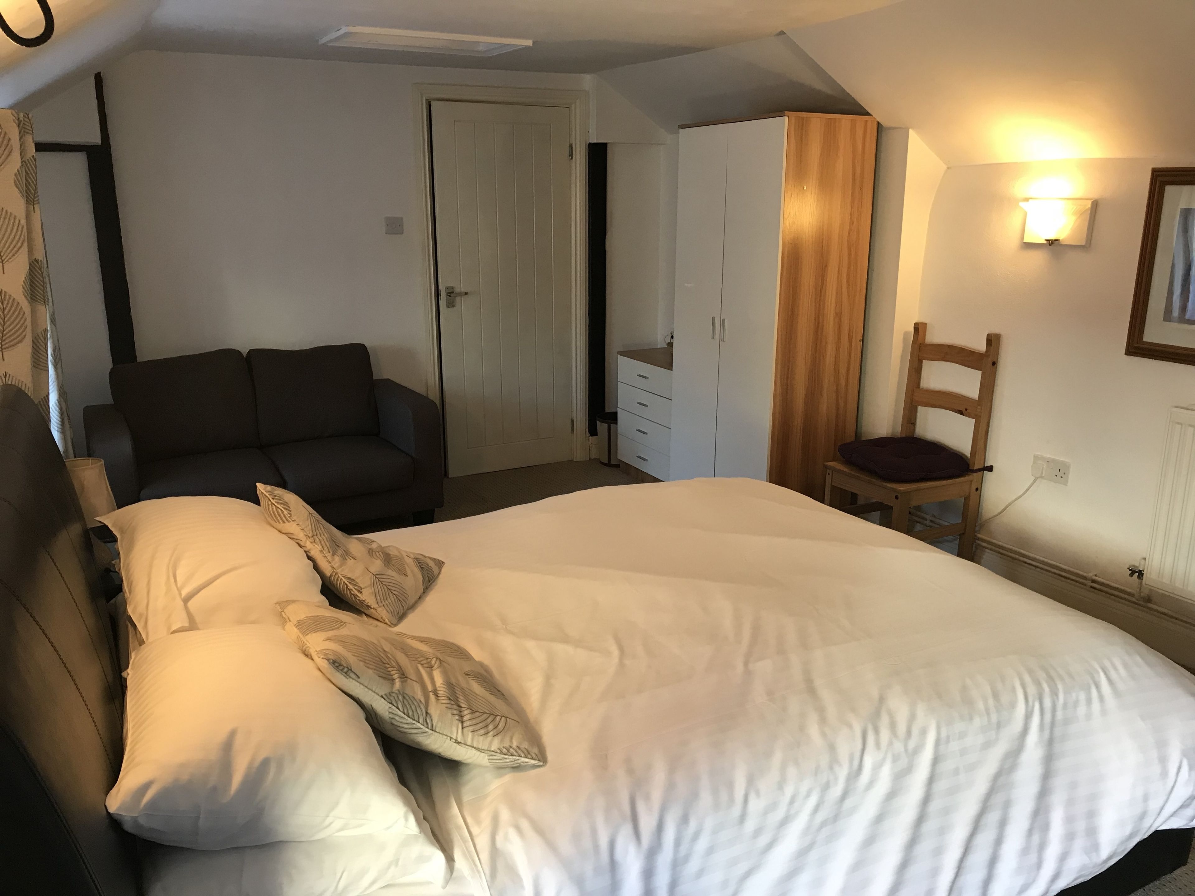 Una camera da letto con un letto, un divano, un armadio e una sedia.