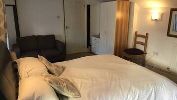 Una camera da letto con un letto, un divano, un armadio e una sedia.