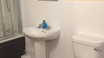 A bathroom with a shower, sink, toilet, and a mirror above the sink.