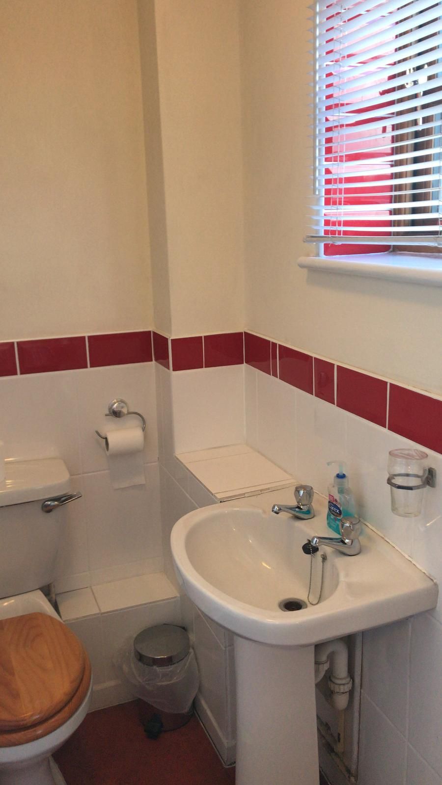 Un baño con inodoro, lavamanos y ventana con persianas.