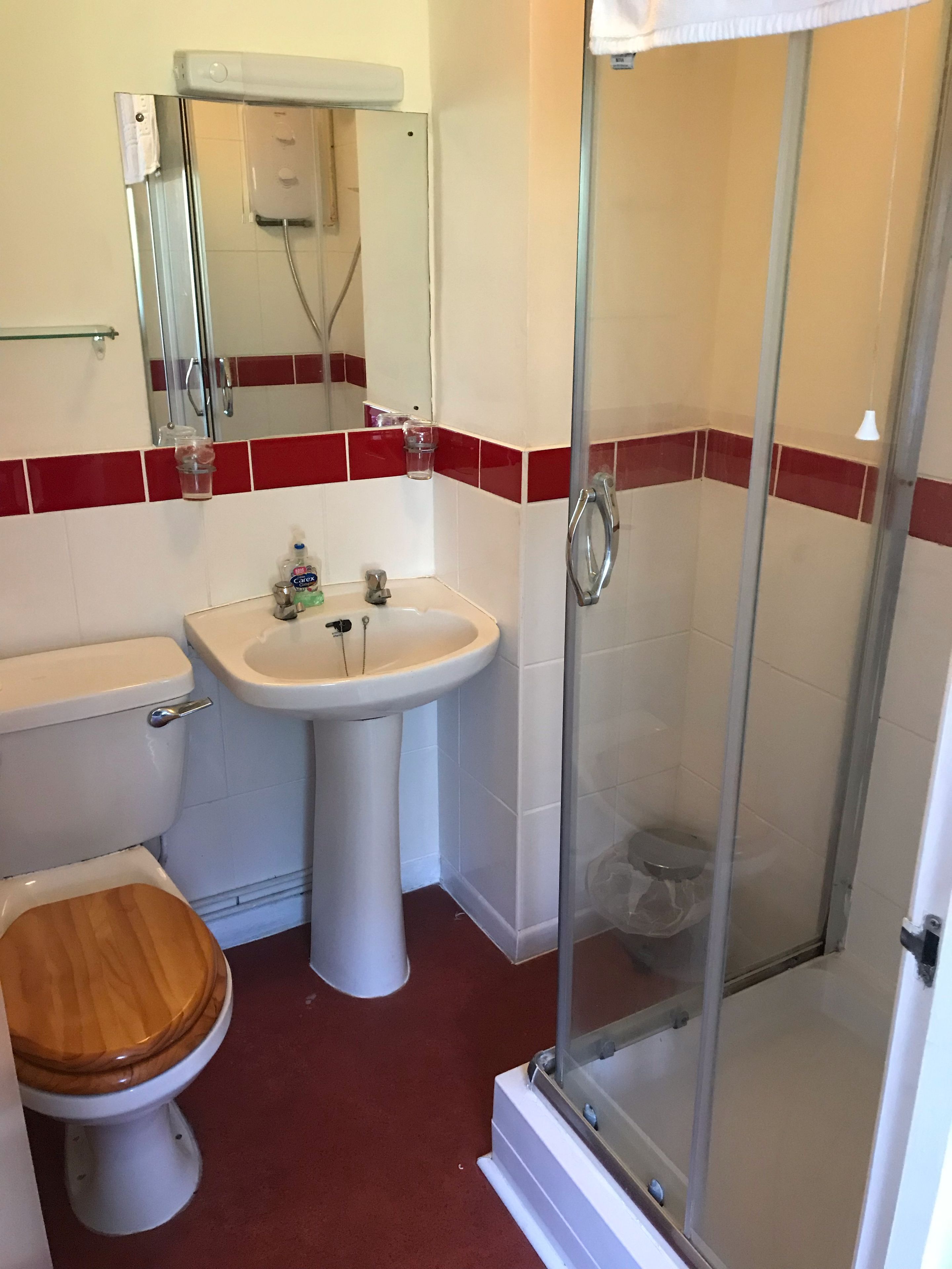 A bathroom with a toilet, sink, and glass shower enclosure.