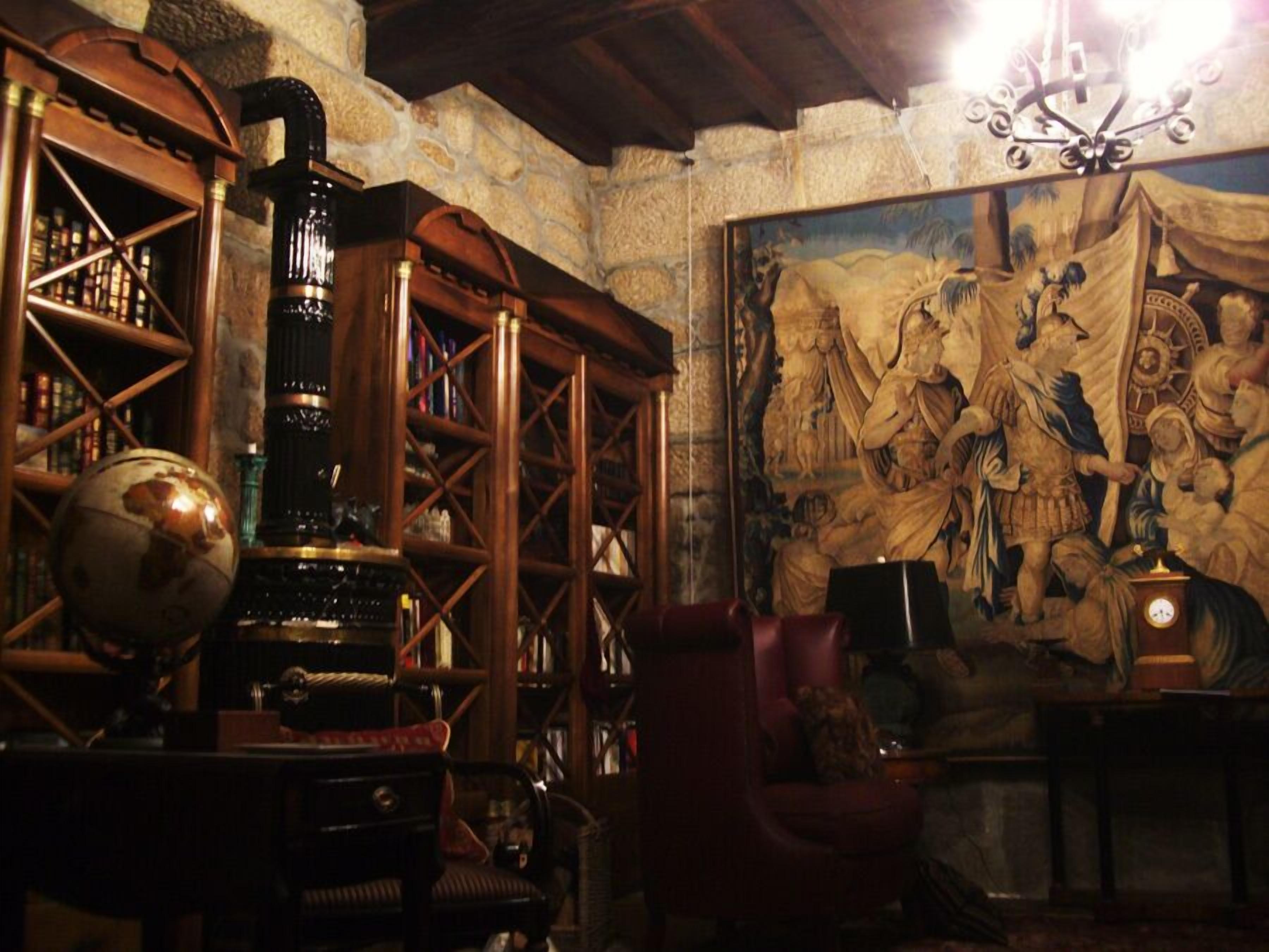 A room with a large globe, bookshelves, a vintage clock, and a mural.