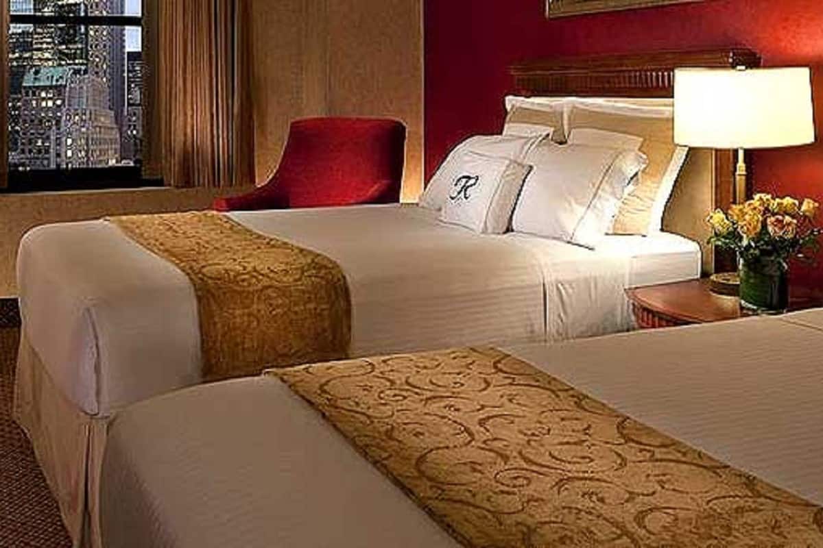 Een hotelkamer met twee bedden, een bureau, een stoel en uitzicht op de stadszicht.