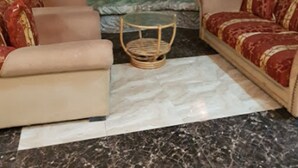A living room with a sofa set, a coffee table, and a decorative rock wall. - Hotel Bouazza (Tiaret)