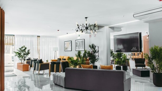 A modern hotel lobby with a grey sofa, wooden accents, and potted plants. - Masa Hotel 5 de Outubro (Lisbon)