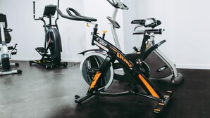 A stationary bike in a gym with a black and orange color scheme. - Masa Hotel 5 de Outubro (Lisbon)