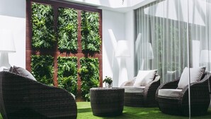 A modern outdoor seating area with wicker furniture and a vertical garden wall. - Masa Hotel 5 de Outubro (Lisbon)