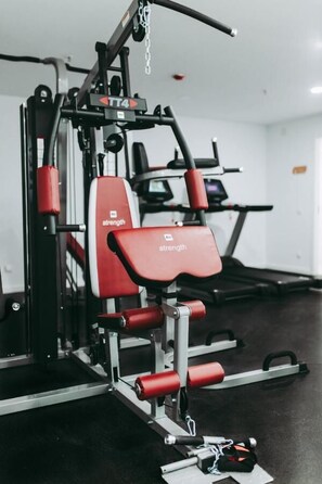 A gym with a strength training machine, a treadmill, and a weight bench. - Masa Hotel 5 de Outubro (Lisbon)