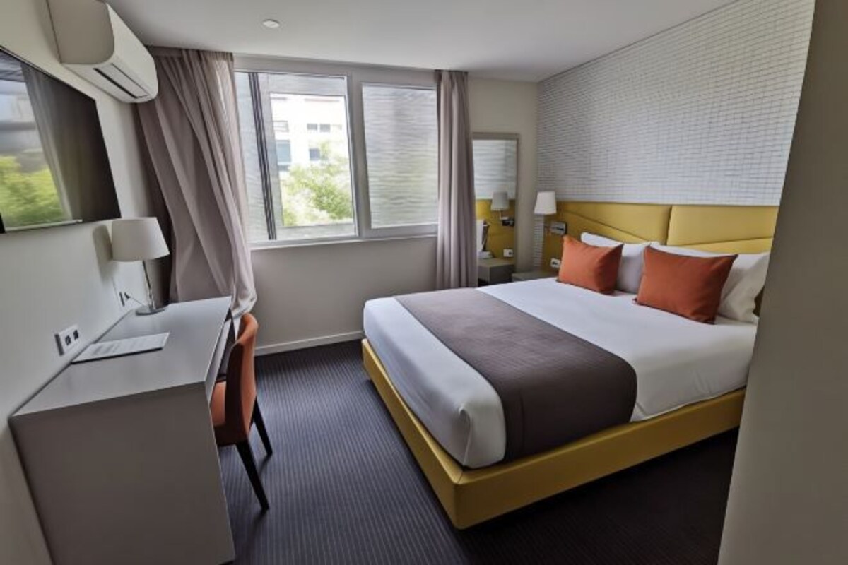 A hotel room with a bed, desk, and chair.