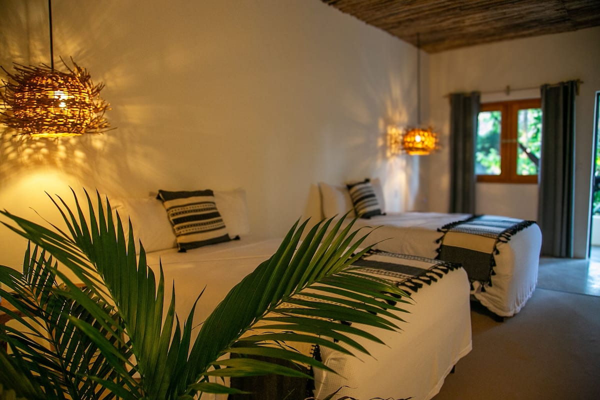 Un dormitorio con cama, almohadas y una lámpara colgante.