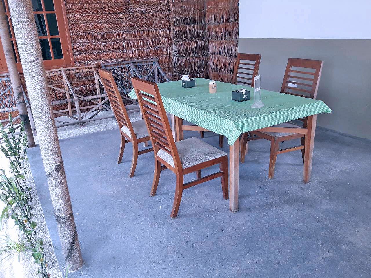 Ein Tisch ist mit einer grünen Tischdecke, Holzstühlen und einigen Gegenständen gedeckt.