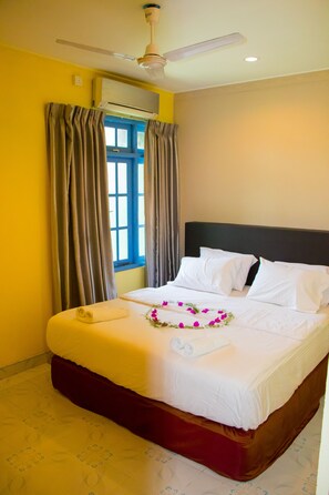 Une chambre d’hôtel équipée d’un lit, de rideaux, d’un ventilateur de plafond et d’un appareil de climatisation.