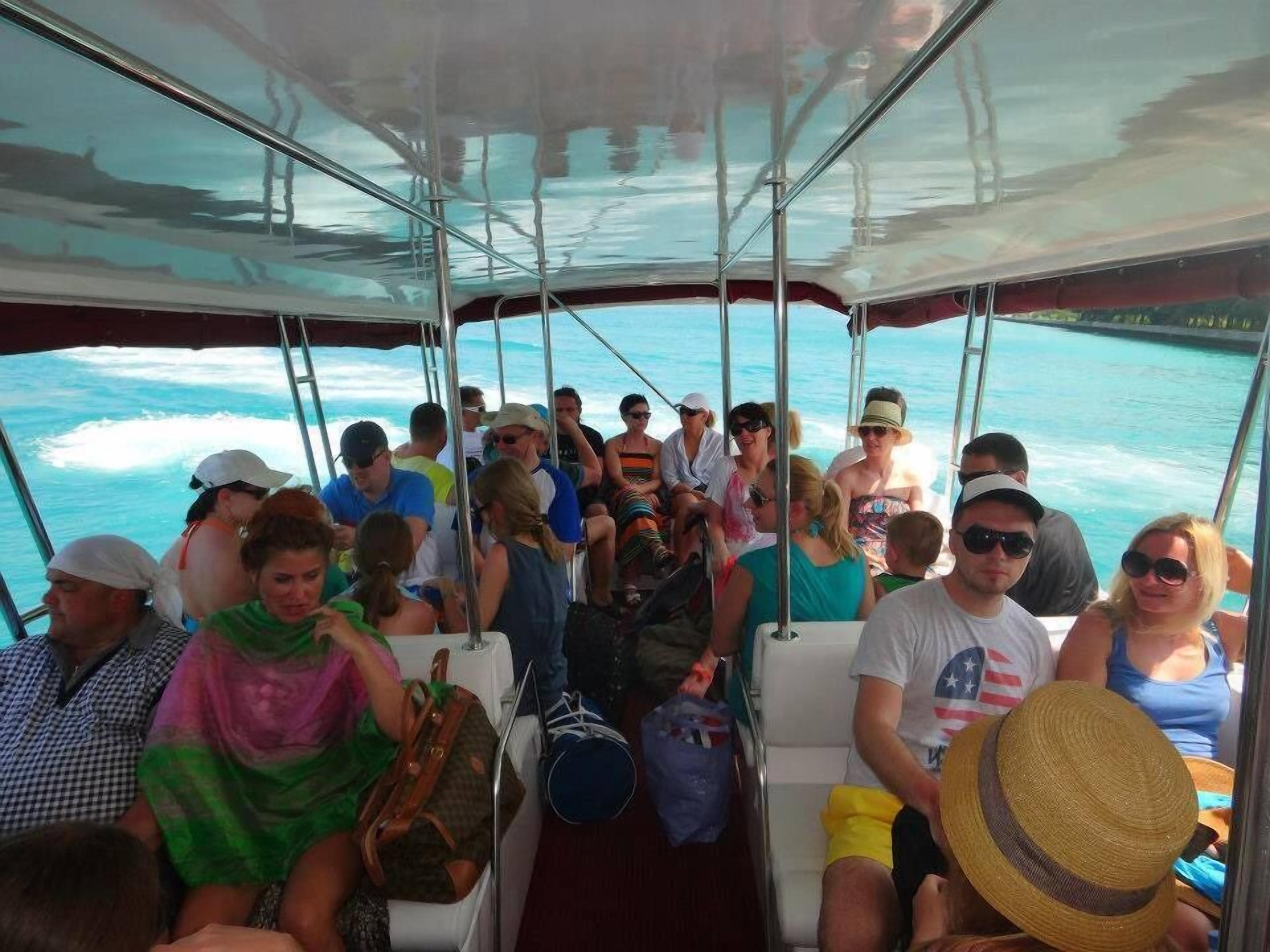 A boat with passengers seated inside, facing the ocean.