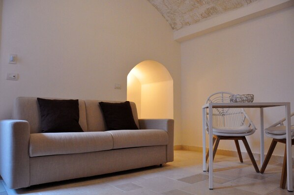 A living room with a sofa, two chairs, a table, and a wall-mounted light fixture. - Donna Piera - Dimore di Charme (Monopoli)