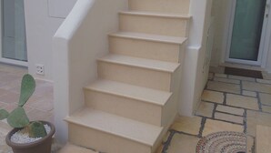 Een trap met beige treden die naar een deur met een ruit loopt.
