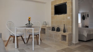 Een eethoek met een tafel en stoelen, een flatscreen televisie bevestigd aan een stenen muur, en een open haard met hangende decoraties.