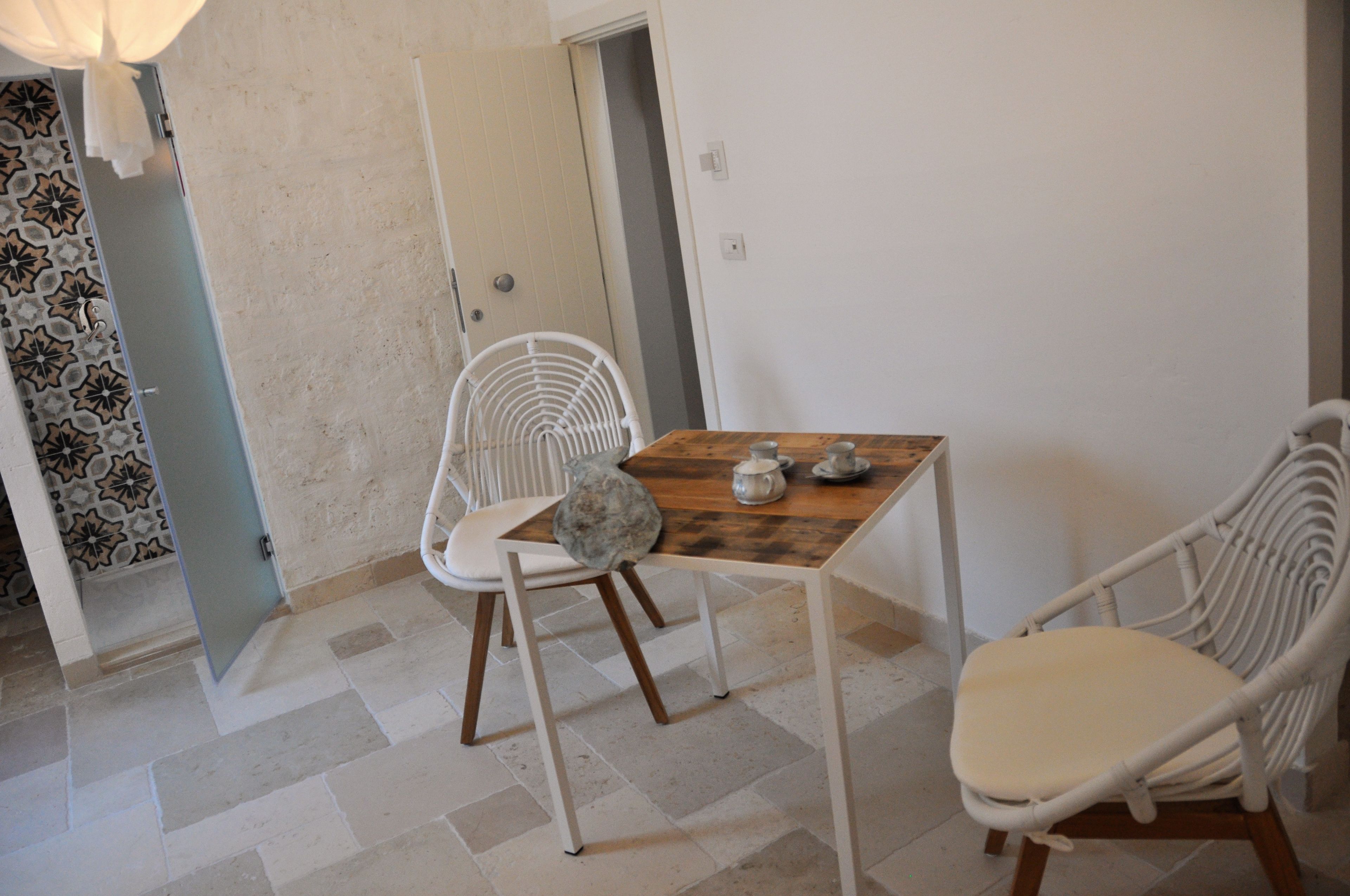 Un pequeño comedor con una mesa de madera y dos sillas blancas.