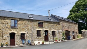 A stone building with multiple windows and doors, a paved street, and outdoor seating. - The Wagon House (Launceston)