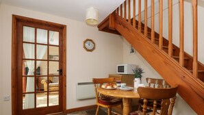 A dining area with a wooden table, chairs, a clock, and a staircase. - The Wagon House (Launceston)